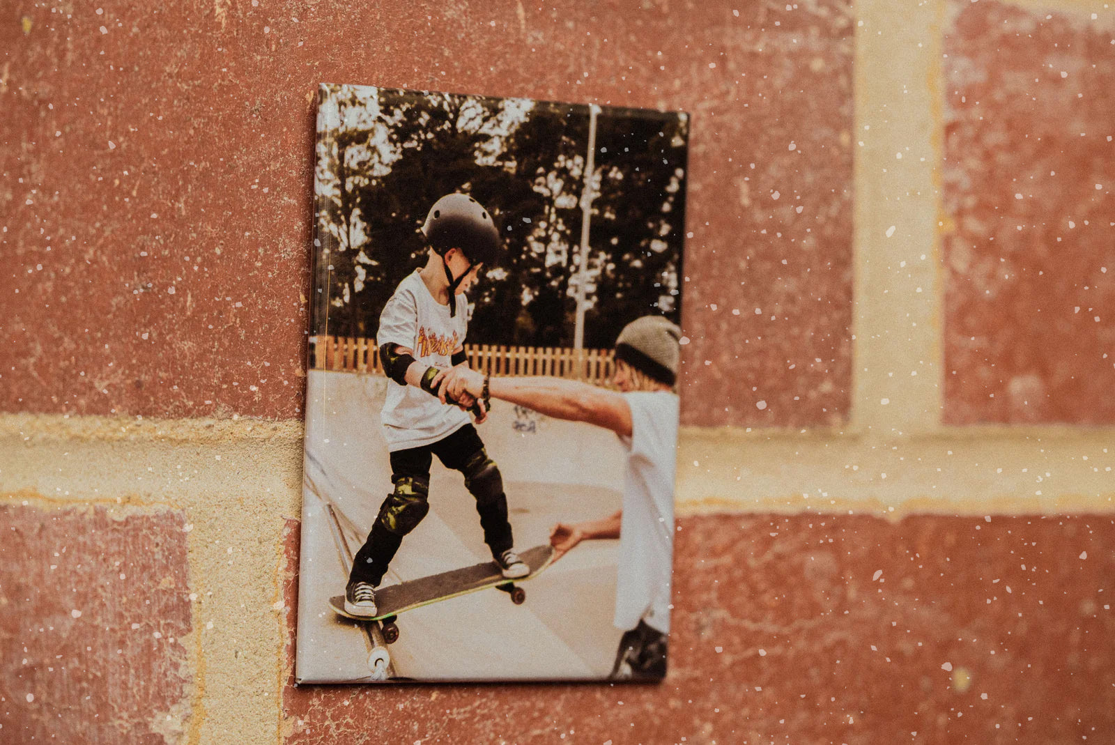 A magnet printed with a photo of a father helping his son on a skateboard.