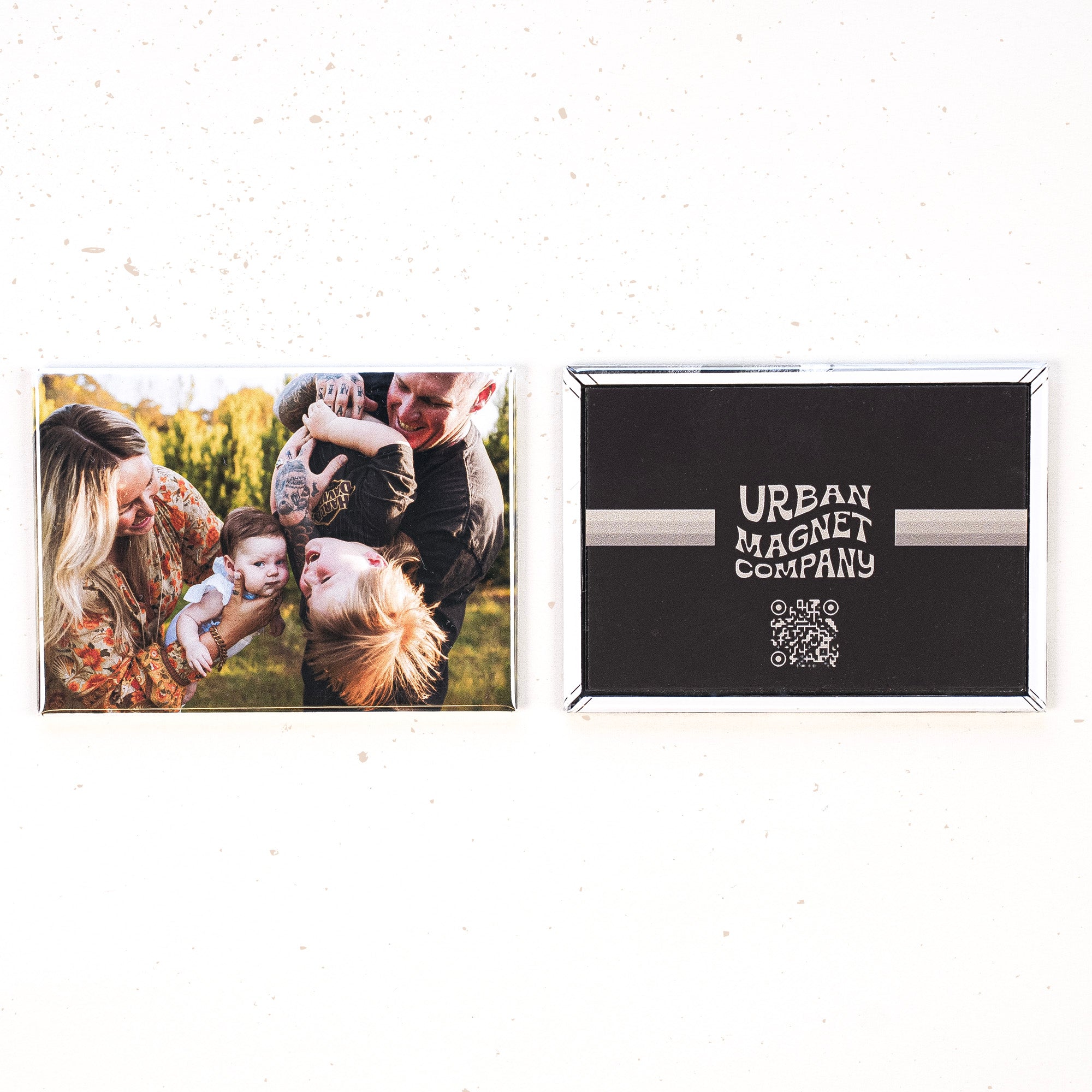 Two magnets on a white background, one is printed with a family photo, the other is printed with the Urban Magnet Co logo.