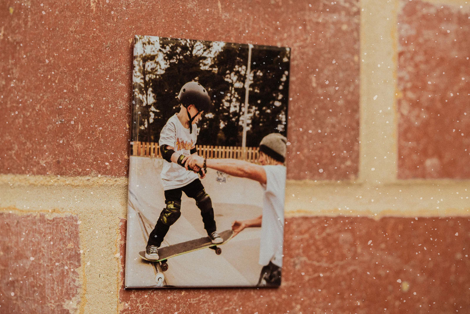 A magnet printed with a photo of a father helping his son on a skateboard. 